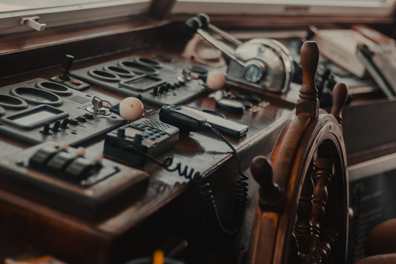 services-09 Vintage boat control panel with various gadgets and a wooden steering wheel.